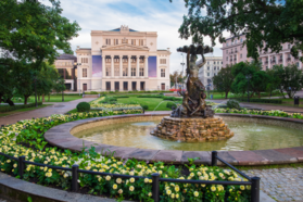 Lush garden with fountain in front of Latvian National Opera Ballet House, adding to its elegant ambiance