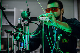 A man in glasses works with a laser equipment at a physics-related research facility