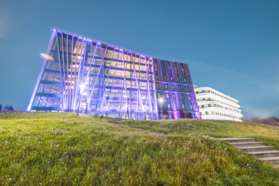University of Latvia's Academic Centre with grassy foreground. Houses of Nature and Science stand out, one illuminated in purple